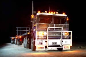Mack heavy-duty truck with flashing lights parked on the road at night.