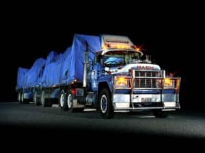 Heavy haul truck transporting large cargo on a flatbed at night.