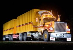 A large yellow freight truck with a container, illuminated against a dark night sky, emphasizing logistics and transportation services. Heavy-duty freight truck with yellow container, illuminated at night, showcasing robust transport ca.