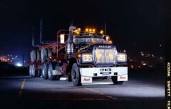 Nighttime image of a Mack truck ready for transport or delivery, showcasing robust design and lighting features. Heavy-duty Mack truck with illuminated lights parked on the road.